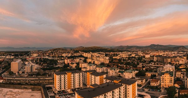 A street-level view of Podgorica, Montenegro, showing modern architecture and surrounding mountains