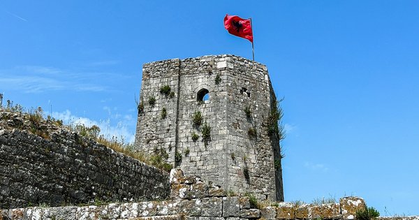 Old stone buildings and a lake shoreline in northern Albania near mountains