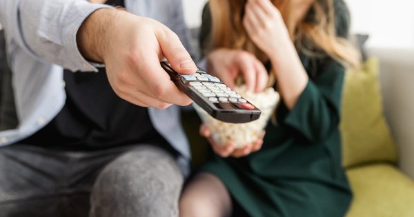 A close-up of a TV remote control resting on a couch with soft evening light