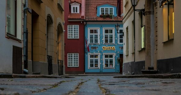 A row of colorful historic buildings along a cobblestone street in Riga, Latvia